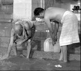 Fader og sønnen henter vand fra floden Ganges, Indien 